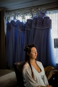 bride getting ready with bridesmaids dresses in the background