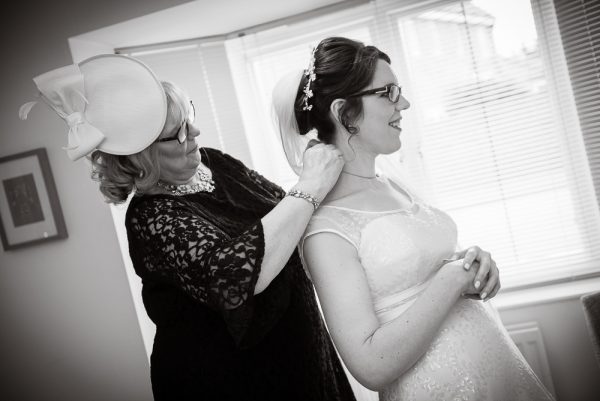 mother of the bride attaches necklace to bride