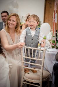 little boy standing on chair looking at person giving speech