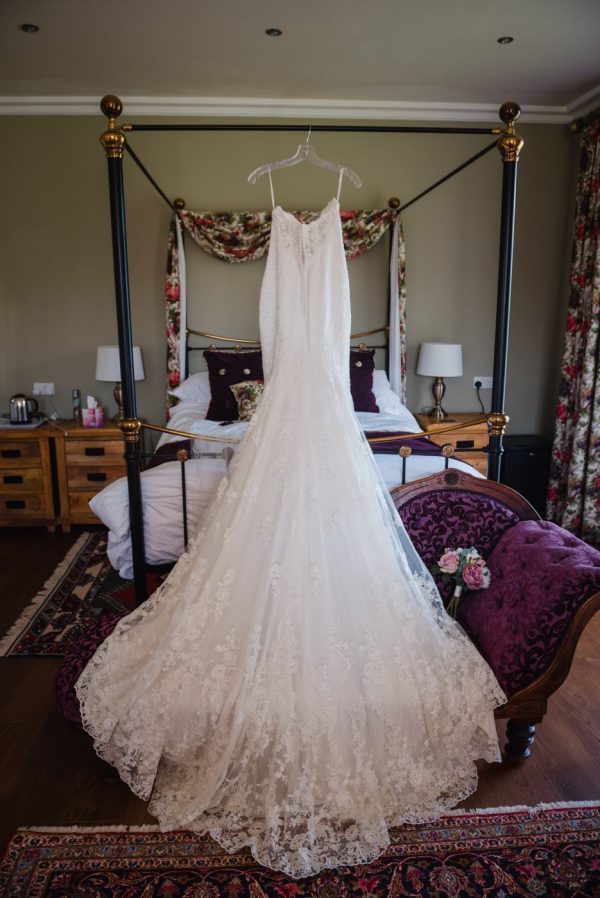 wedding dress hung up on four poster bed