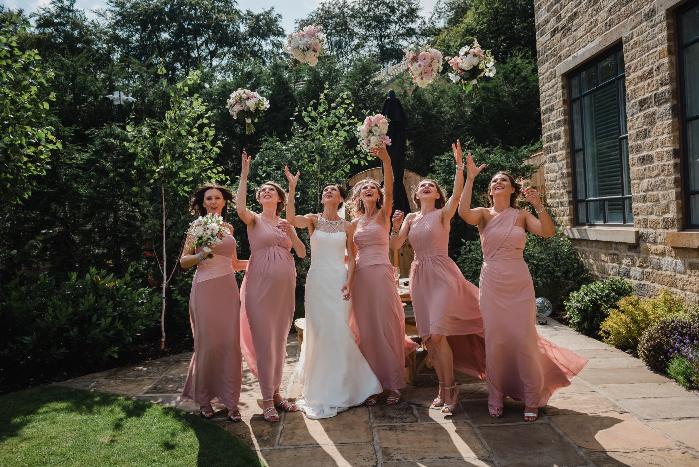 bridesmaids dressed in pink throw their bouquets