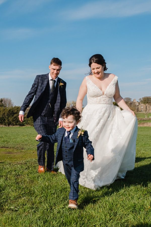 bride and groom run after their son in a suit little suit