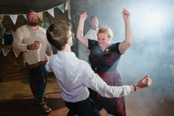 lady dances with a man in white shirt bunting and smoke in the background