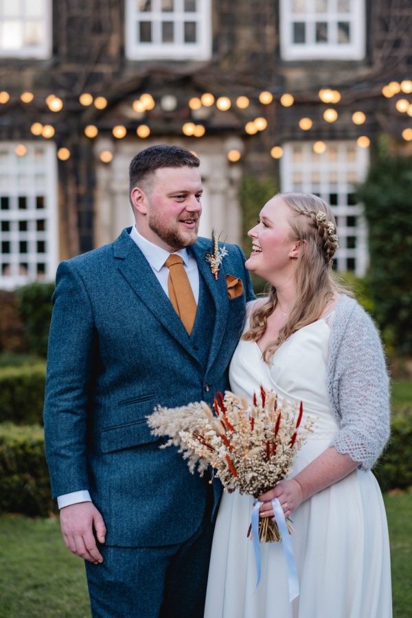 outdoor portraits of the wedding couple at their winter wedding fairy lights in the background