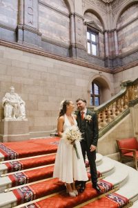 bride and groom standing at the bottom of a large sweeping staircase inside Sheffield Town Hall